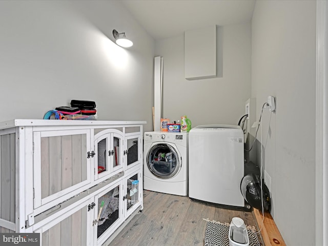 clothes washing area with cabinets, independent washer and dryer, and wood-type flooring