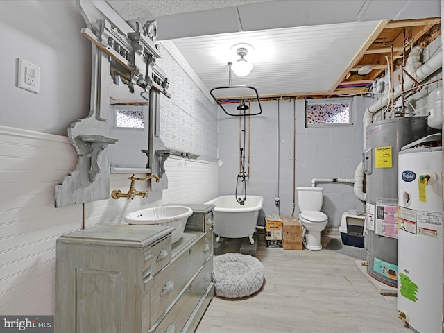 bathroom featuring wood-type flooring, vanity, a bath, electric water heater, and water heater