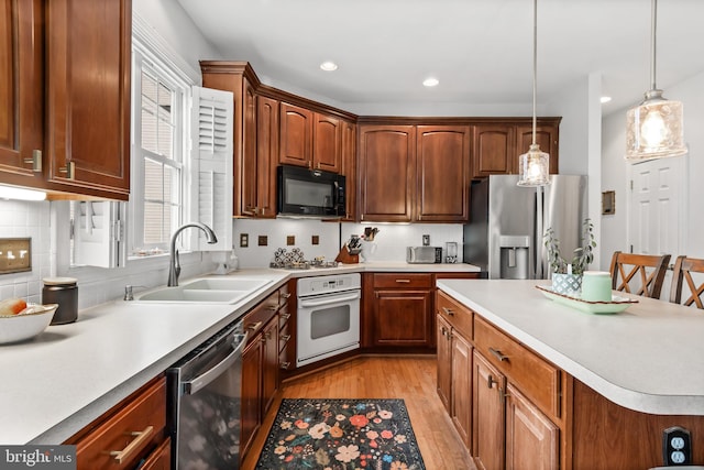 kitchen featuring pendant lighting, sink, light hardwood / wood-style flooring, stainless steel appliances, and tasteful backsplash