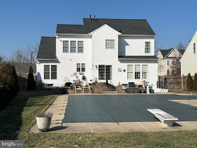 rear view of property featuring a yard, a patio area, and a covered pool