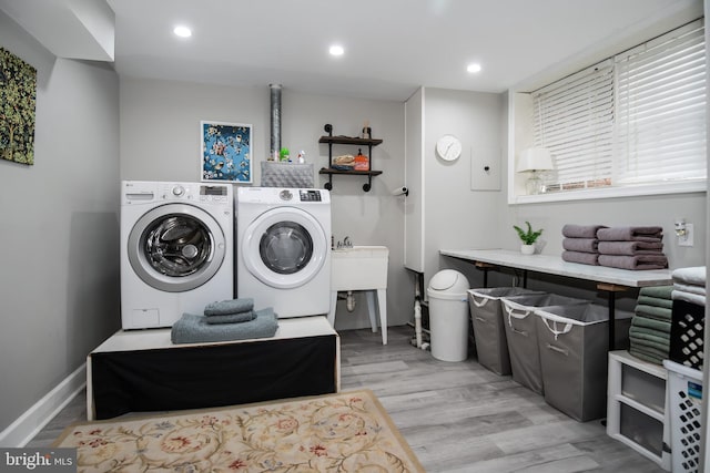 clothes washing area featuring separate washer and dryer and light hardwood / wood-style floors