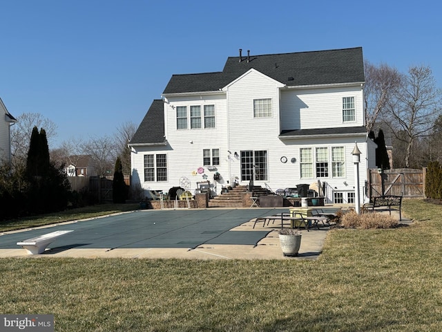 back of property with a patio, a covered pool, and a yard