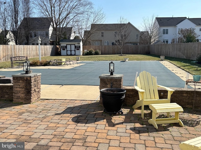 view of swimming pool featuring a patio area, a lawn, and a storage unit