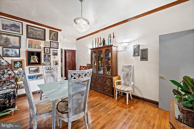 dining area featuring a notable chandelier, crown molding, and light hardwood / wood-style flooring