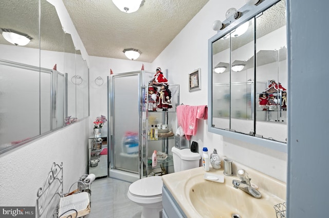 bathroom with vanity, toilet, a shower with shower door, and a textured ceiling