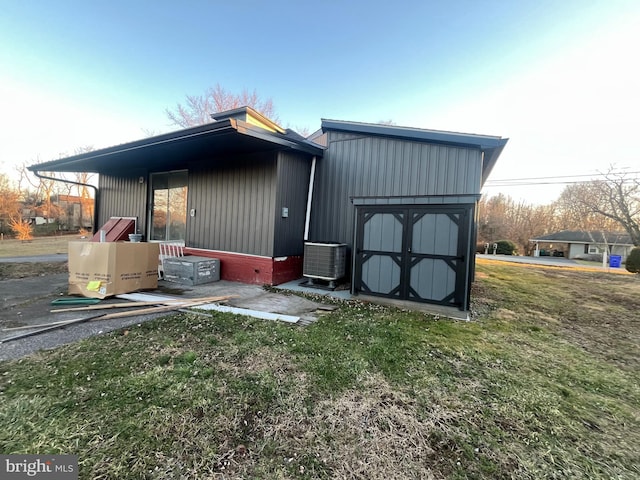 view of outbuilding featuring central AC unit and a lawn