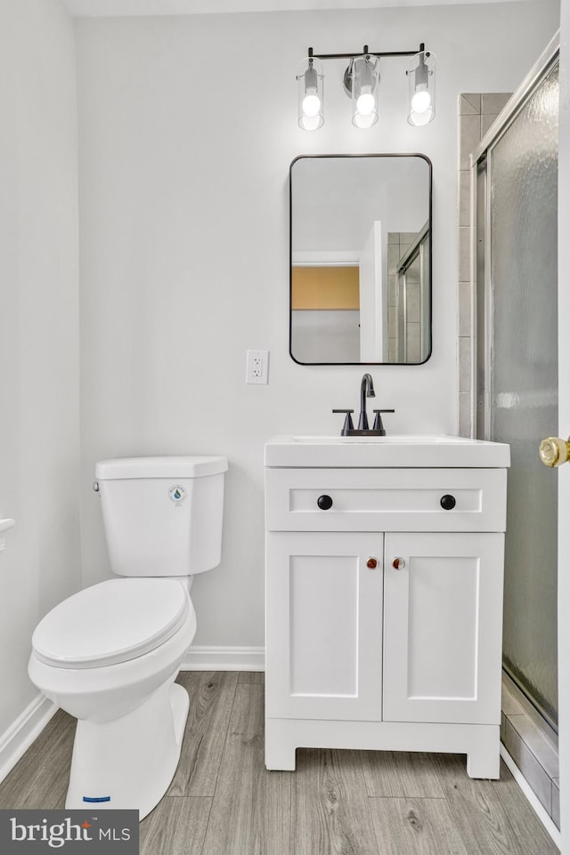 bathroom with vanity, wood-type flooring, a shower with door, and toilet