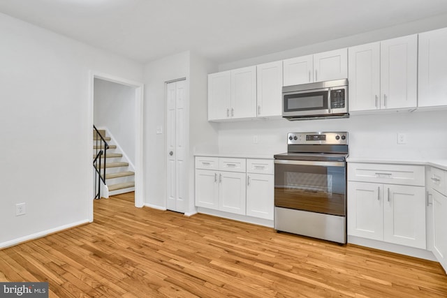 kitchen with white cabinetry, appliances with stainless steel finishes, and light hardwood / wood-style flooring