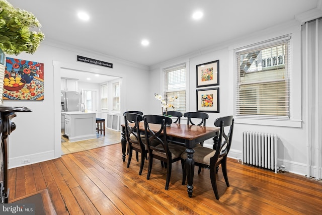 dining area featuring crown molding, radiator heating unit, and light hardwood / wood-style floors