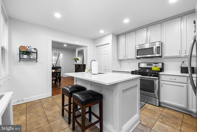 kitchen featuring a breakfast bar, tasteful backsplash, sink, a kitchen island with sink, and stainless steel appliances