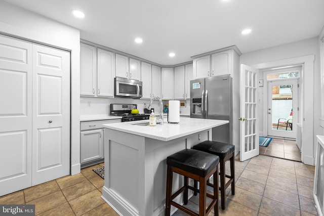 kitchen featuring a kitchen bar, sink, stainless steel appliances, a kitchen island with sink, and backsplash