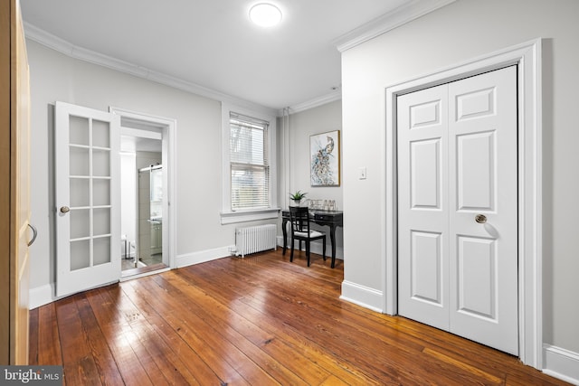 unfurnished room with crown molding, radiator heating unit, and wood-type flooring