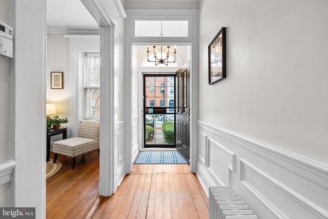 foyer entrance featuring an inviting chandelier, crown molding, and light wood-type flooring