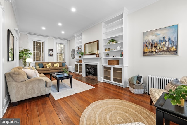 living room with crown molding, radiator heating unit, built in features, and dark wood-type flooring