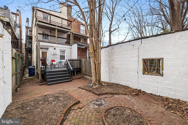 rear view of property with a wooden deck, a balcony, and a patio area