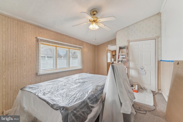 bedroom with carpet floors, ornamental molding, ceiling fan, and wood walls