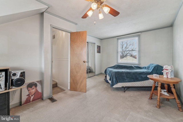 bedroom featuring light colored carpet, ceiling fan, and a closet