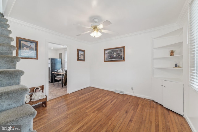 interior space with ceiling fan, ornamental molding, and wood-type flooring