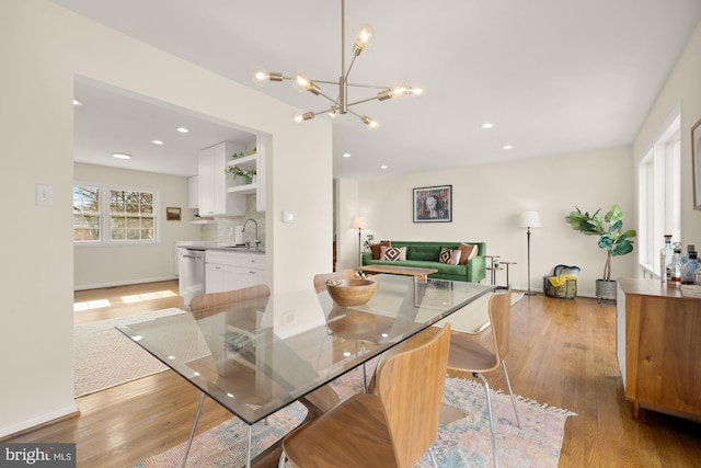 dining area featuring a chandelier, sink, and light wood-type flooring