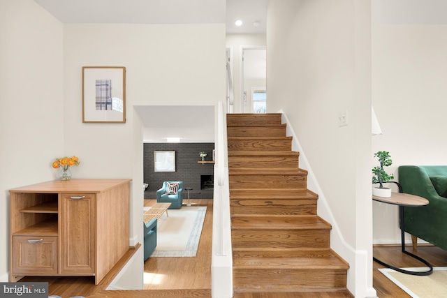 staircase with wood-type flooring and a fireplace