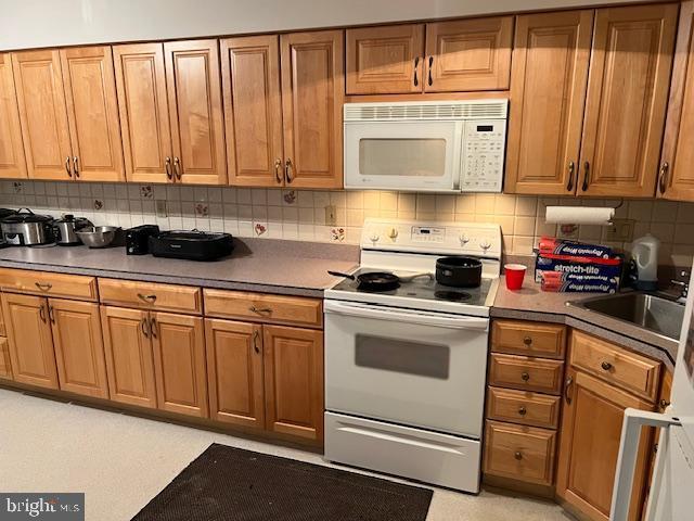 kitchen with tasteful backsplash, sink, and white appliances