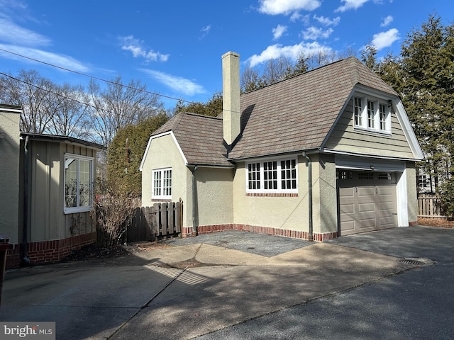 exterior space with a garage, fence, driveway, stucco siding, and a chimney