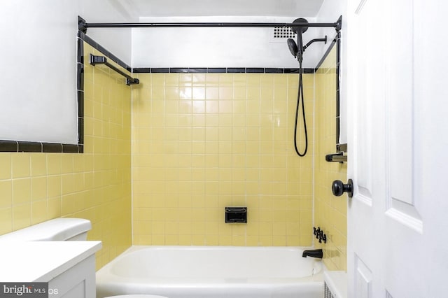 full bathroom featuring vanity, tiled shower / bath combo, and toilet