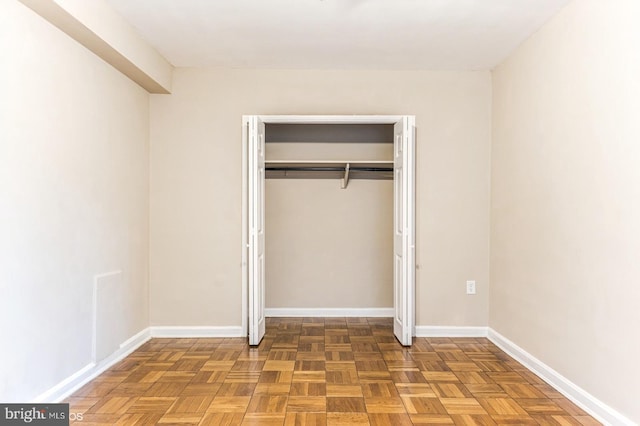 unfurnished bedroom featuring parquet floors and a closet