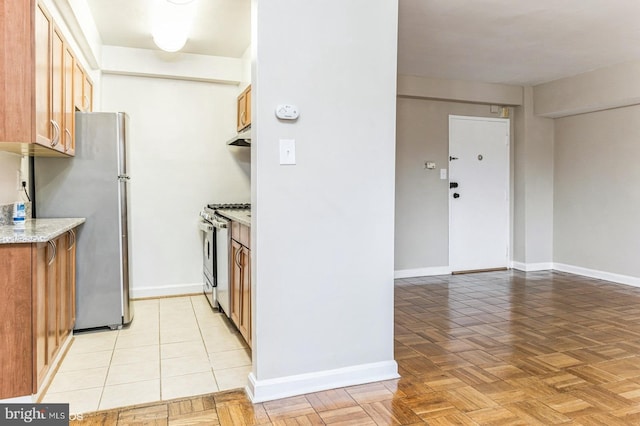 kitchen with light stone counters, stainless steel appliances, and light parquet flooring