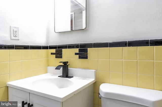 bathroom with vanity, toilet, and tile walls