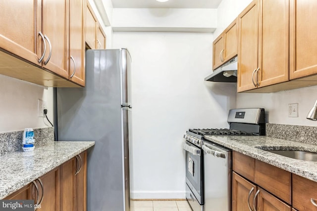 kitchen with sink, light tile patterned floors, light stone countertops, and appliances with stainless steel finishes