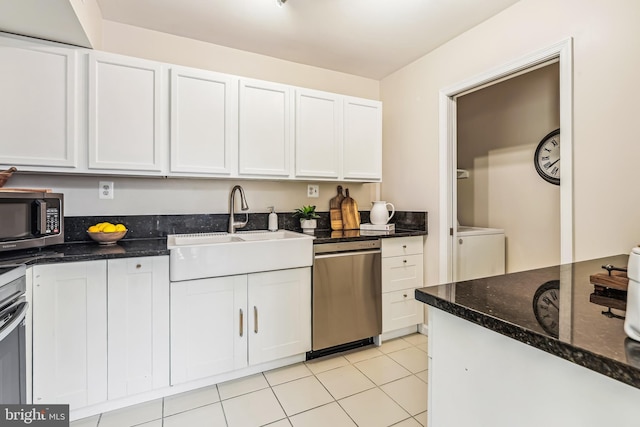 kitchen featuring dishwasher, sink, dark stone countertops, and white cabinets