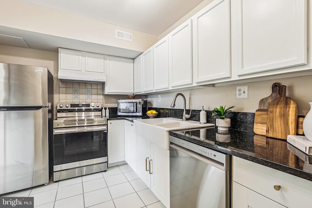 kitchen with white cabinetry, appliances with stainless steel finishes, sink, and dark stone counters