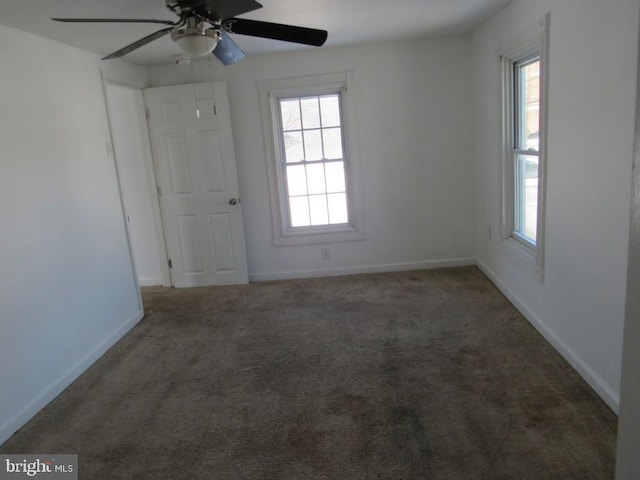 spare room with a wealth of natural light and dark colored carpet