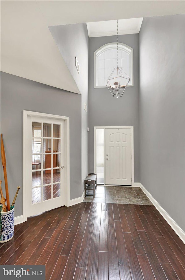 foyer featuring ornamental molding, dark wood-type flooring, a chandelier, and a towering ceiling