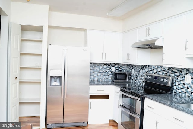 kitchen with light hardwood / wood-style flooring, dark stone countertops, stainless steel appliances, white cabinets, and decorative backsplash