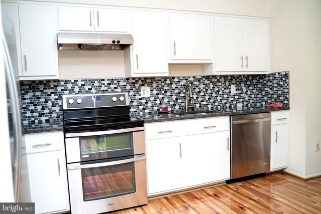 kitchen with dark stone countertops, appliances with stainless steel finishes, sink, and white cabinets