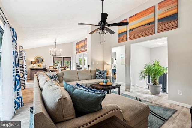 living room with ceiling fan with notable chandelier, light hardwood / wood-style flooring, and high vaulted ceiling