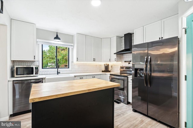 kitchen with sink, wooden counters, white cabinetry, stainless steel appliances, and wall chimney exhaust hood