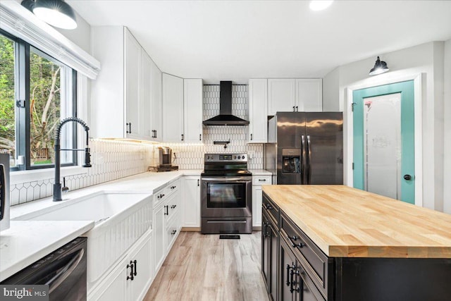 kitchen with wall chimney range hood, sink, stainless steel appliances, white cabinets, and decorative backsplash