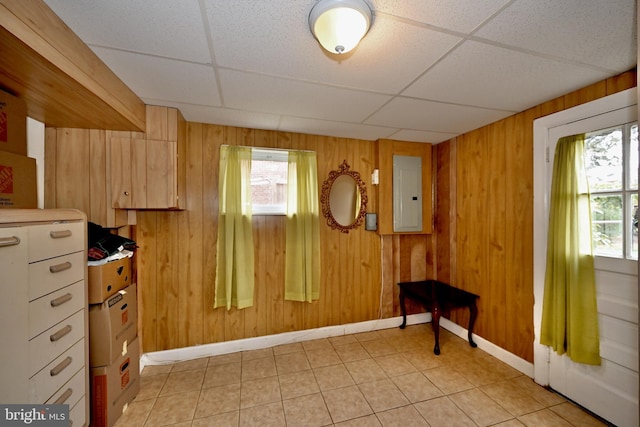 miscellaneous room with a paneled ceiling, wooden walls, electric panel, and light tile patterned floors