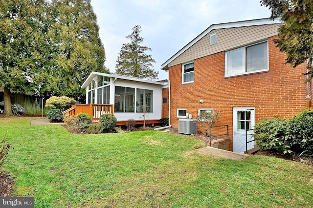 back of property featuring central air condition unit, a sunroom, and a lawn