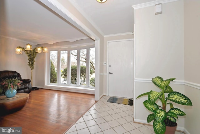 tiled entrance foyer with ornamental molding and an inviting chandelier