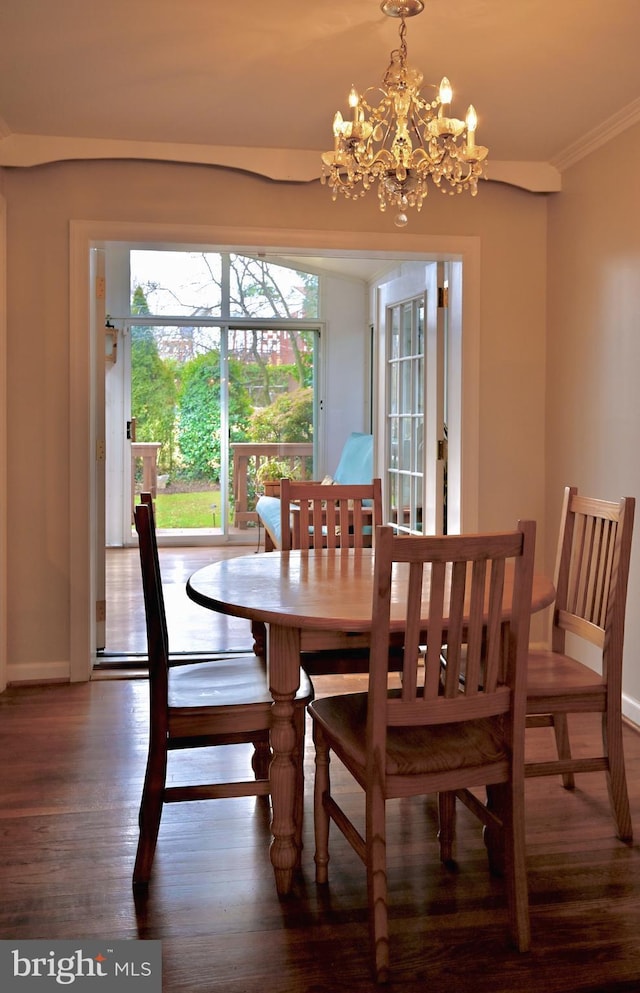 dining room featuring crown molding, dark wood-type flooring, and a chandelier