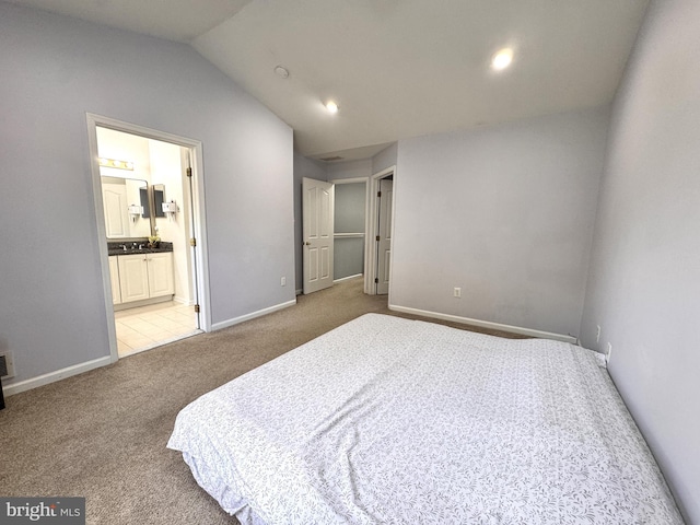 bedroom featuring connected bathroom, vaulted ceiling, and light colored carpet