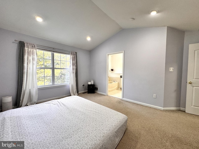 bedroom with light colored carpet, lofted ceiling, and ensuite bathroom