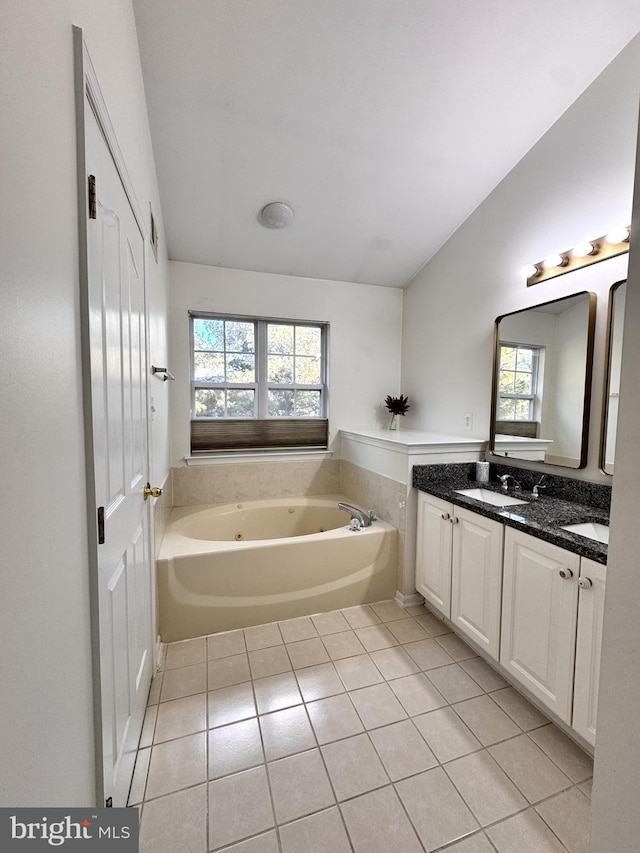 bathroom with vaulted ceiling, vanity, tile patterned flooring, and a washtub