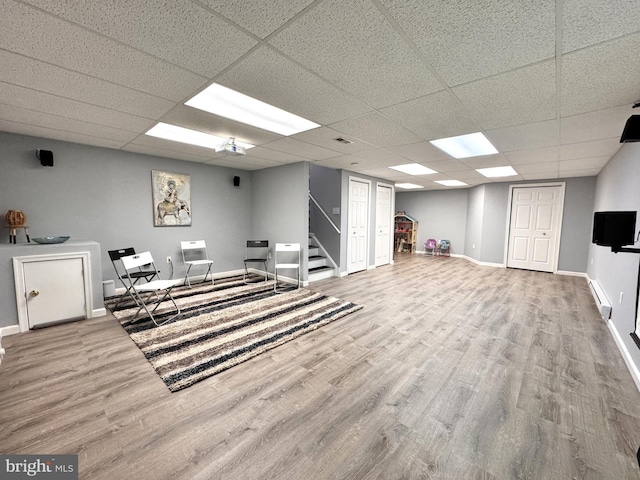 interior space with a paneled ceiling, hardwood / wood-style floors, and a baseboard heating unit