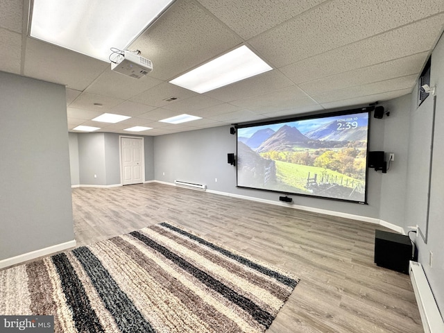 home theater featuring a baseboard heating unit, a paneled ceiling, and light wood-type flooring