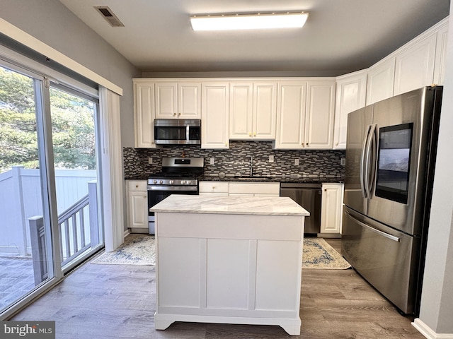 kitchen featuring sink, light wood-type flooring, stainless steel appliances, decorative backsplash, and white cabinets